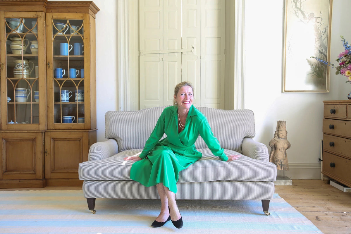 Sophie Conran sitting forward on a striped sofa with her hands on the seat, about to stand